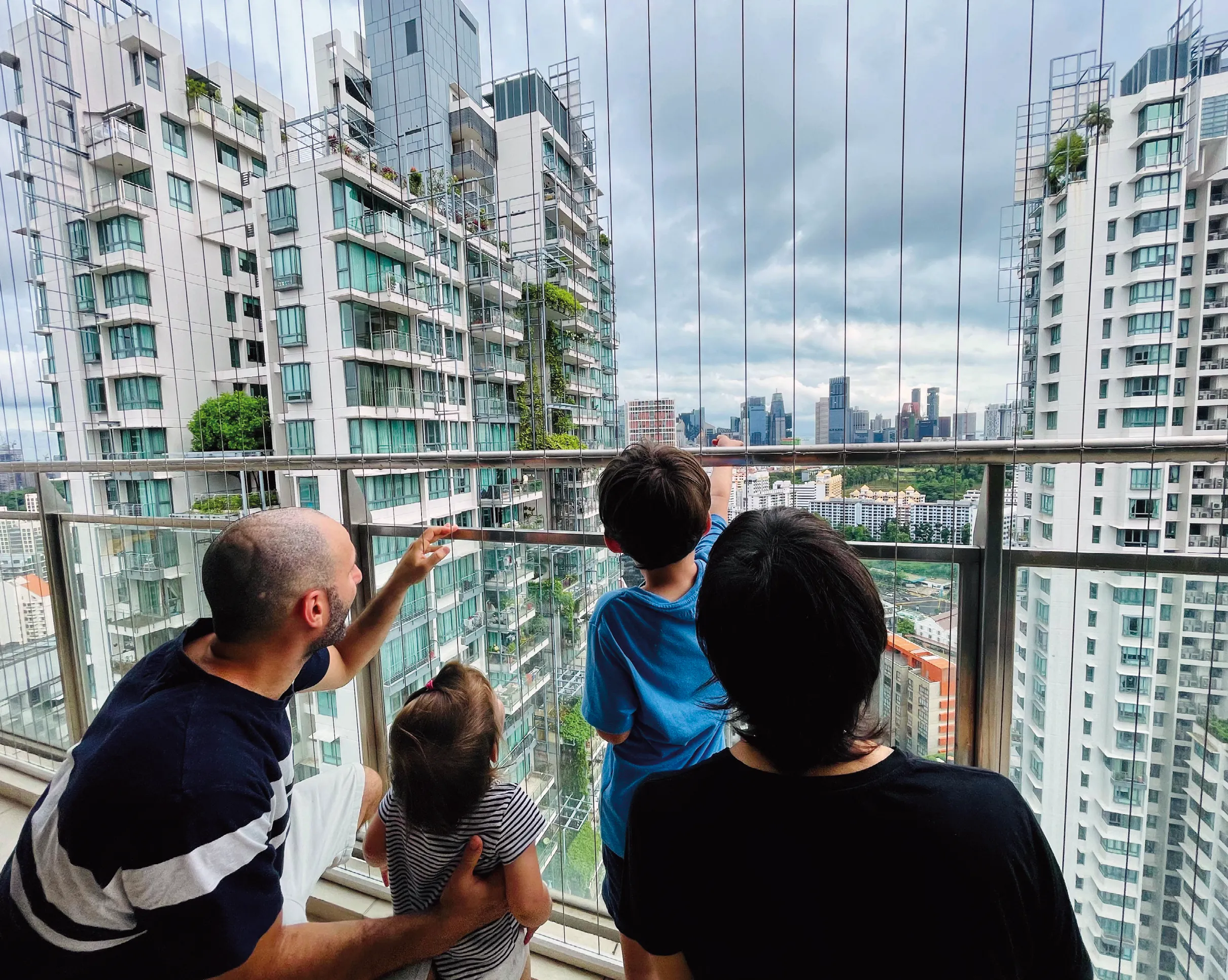 Photo famille expatriés balcon, admirent vue ville, immeubles modernes